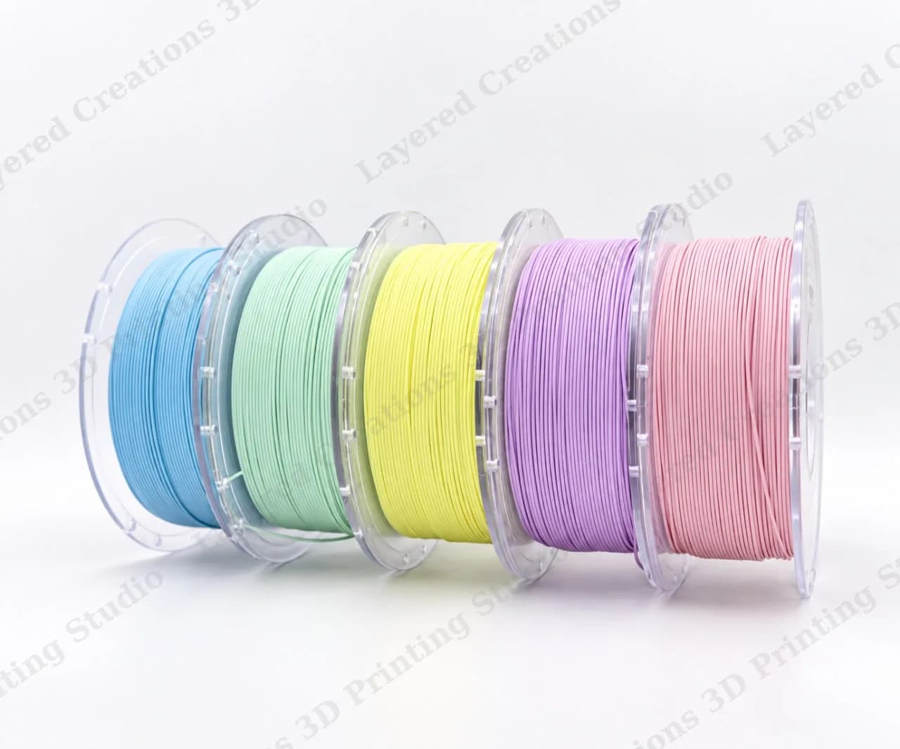 Five spools of pastel-coloured PLA filament in blue, mint green, yellow, lilac and pink
